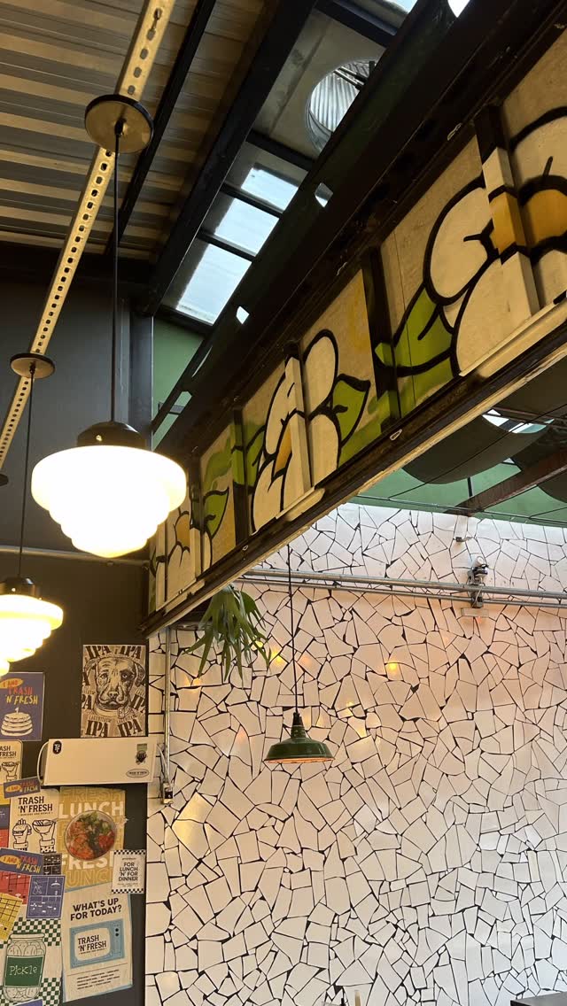 Viga com painel pintado de flores brancas e folhas verdes, acima da parede de mosaico e de luminárias pendentes