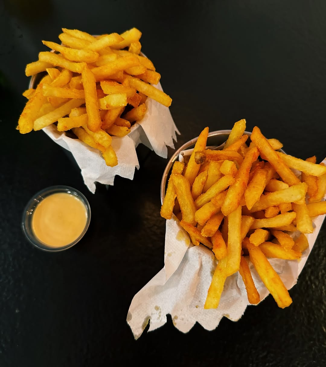 Duas cestinhas de batata frita com páprica e um potinho de maionese, vistas de cima